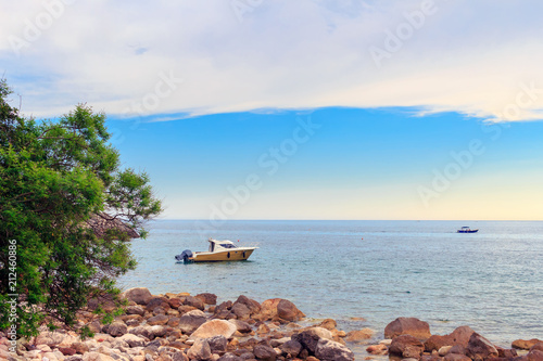 Adriatic sea coastline near Budva city in Montenegro, gorgeous seascape with boats in the water and stone beach