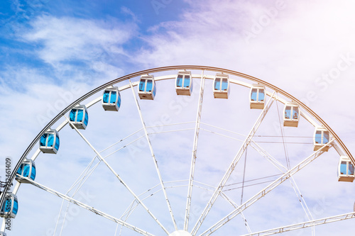 Low angle view of a ferris wheel in an amusement park with a blue sky background. City park ferris wheel in Carousel Gardens. Holiday concept