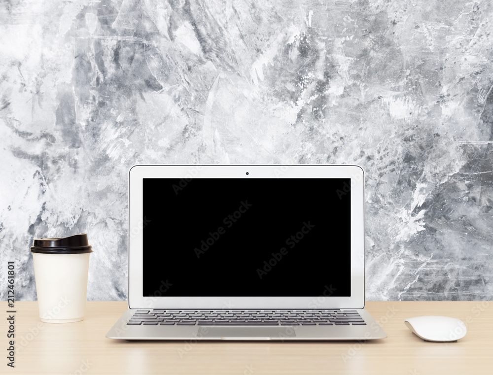 Fototapeta premium Laptop Computer with blank screen on wooden desk with concrete wall background