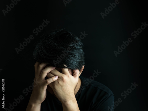 Sad man sitting head in hands isolated on black background. negative thinking concept, emotion portrait