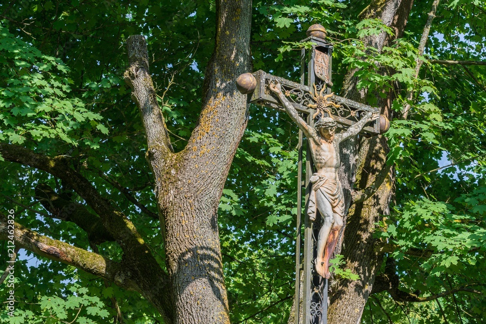 Fototapeta premium Verwittertes Kreuz aus Eisen mit Jesus Statue