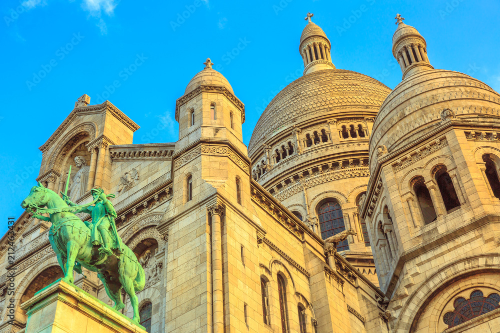 Bottom view of Sacred Heart of Paris church in France. Basilique du Sacre-Coeur de Montmartre. Historic district of Paris city in a beautiful sunny day with blue sky.
