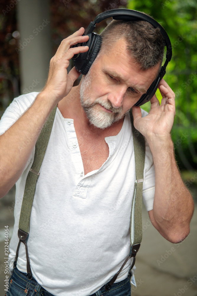 handsome bearded man in his 50s with headphones handsome bearded man in his 50s with headphones