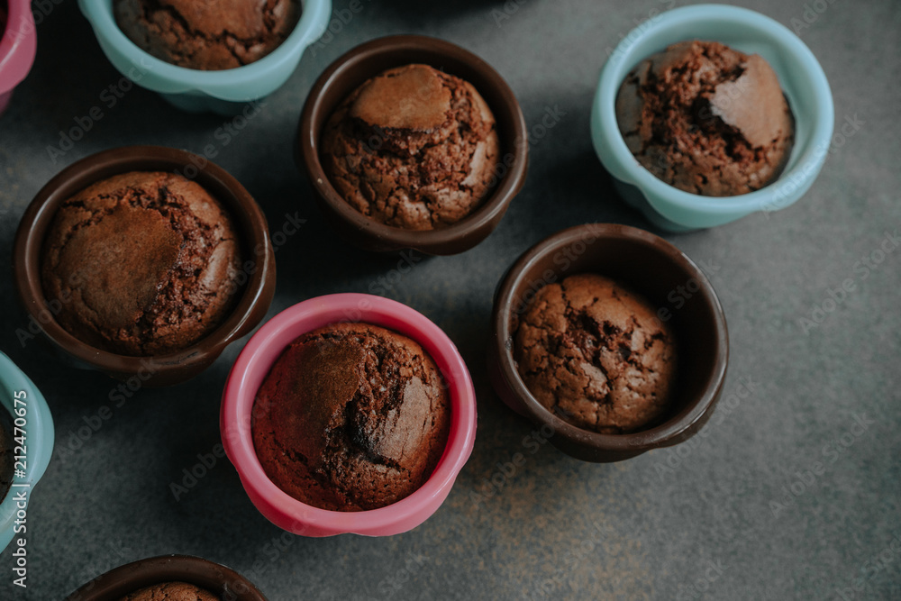 Appetizing chocolate brownie cupcakes in confectionery molds of pink, brown and blue colors. Close up. Appetizing chocolate brownie cupcakes in confectionery molds of pink, brown and blue colors. Close up.