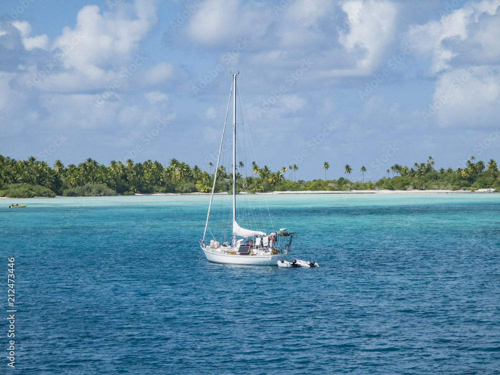 Naklejka premium sailing yacht anchoring in the shallow, turquoise lagoon of Fakarava atoll, Tuamotus archipelago, French Polynesia, south pacific