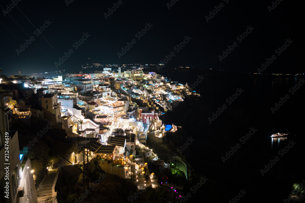 Whitewashed Houses on Cliffs with Sea View and Ships at Night in Imerovigli, Santorini, Greece