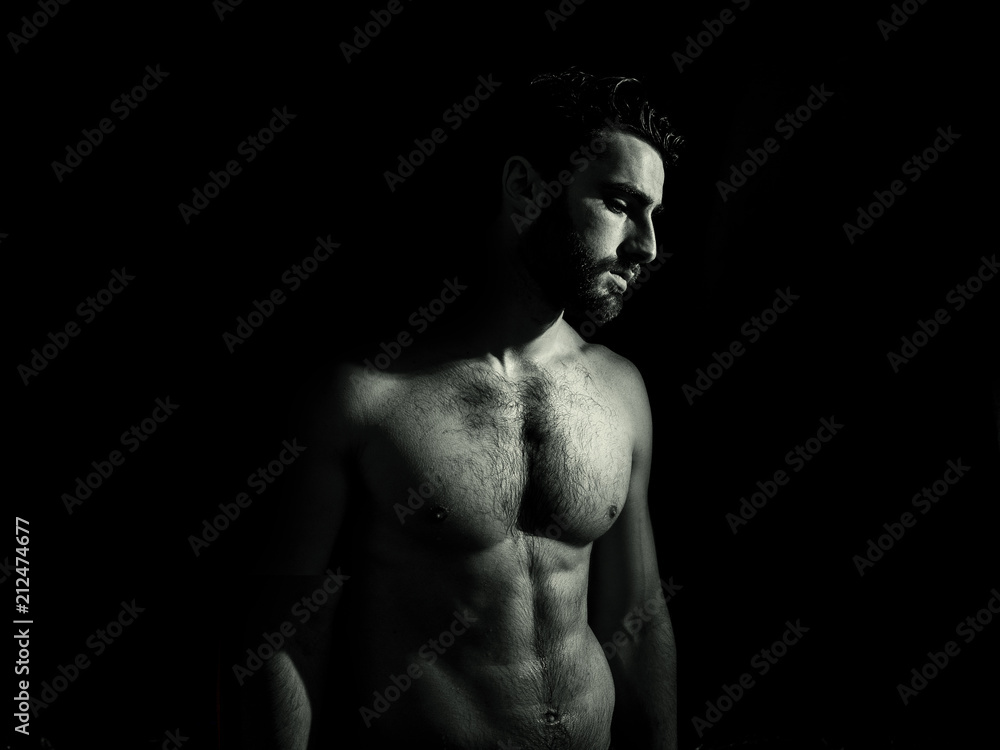 Fototapeta premium Handsome young muscular man shirtless, on black background in studio shot