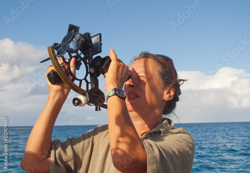 navigator on board of a sailing yacht using a sextant as traditional method of navigation