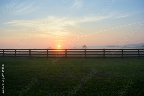 Gorgeous sunrise on a foggy morning along a black rail fence in the Virginia countryside.