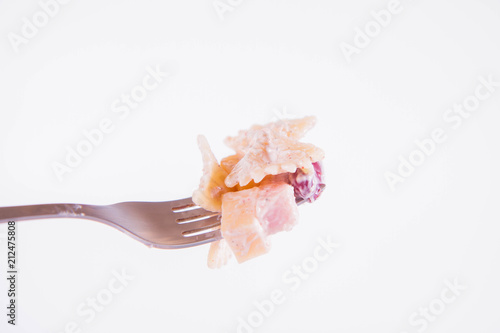 Pasta salad with cheese, ham, kidney beans and mayonnaise on a fork