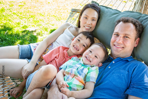 Caucasian Father and Chinese Mother Relaxing In Hammock with Mixed Race Sons