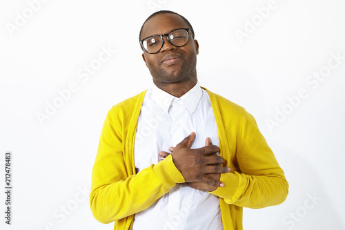 Photography Friendly looking grateful Afro American man keeping hands on his chest, showing sympathy, acknowledgement and gratitude, being in high spirits or flattered