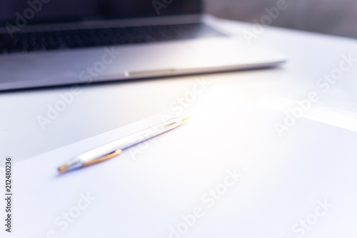 Pen on white paper on table white laptop 