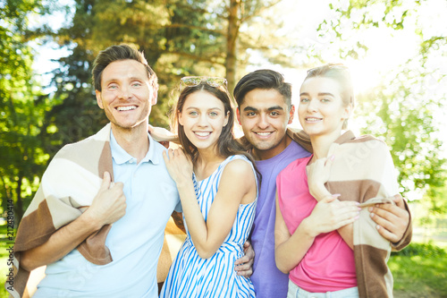 Four joyous teenage friends with plaid enjoying summer vacation in park