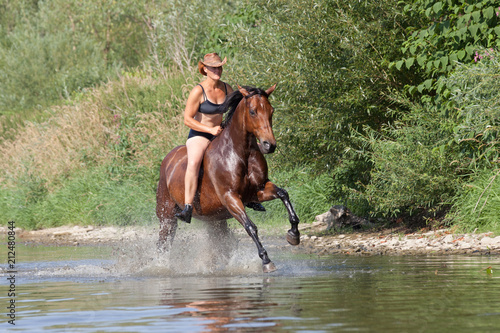 Happy woman galloping in the water