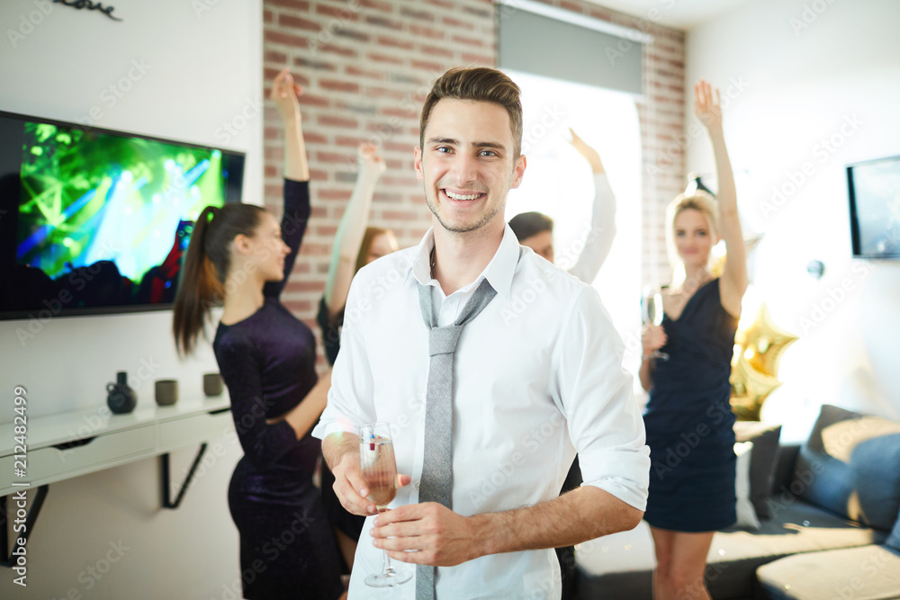 Happy guy in white shirt and grey tie looking at camera with his dancing friends on background Happy guy in white shirt and grey tie looking at camera with his dancing friends on background