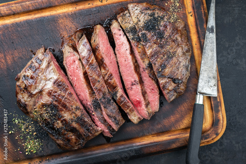 Quadro su tela Barbecue dry aged wagyu flank steak sliced as top view on a burnt cutting with a
