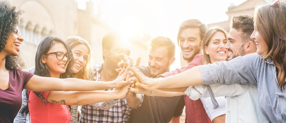 Young millennials friends stacking hands together