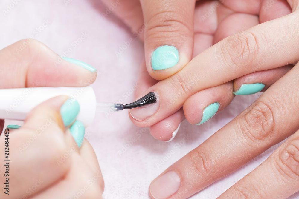 Woman in salon receiving manicure by nail beautician Woman in salon receiving manicure by nail beautician