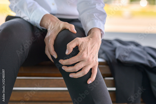 Businesswoman is holding her aching knee