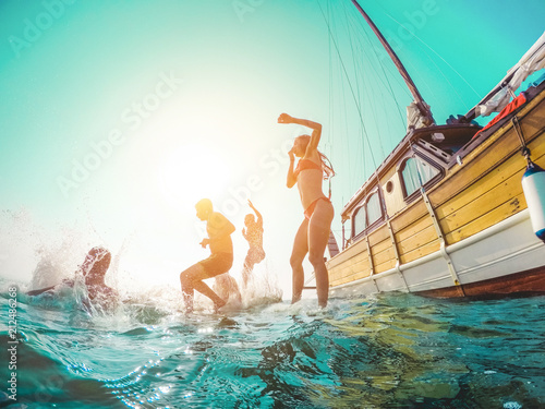 Happy friends diving from sailing boat into the sea