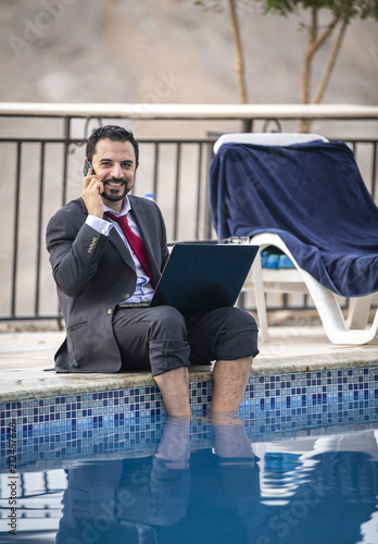 middle aged arab man by a pool working  in his business suit photo