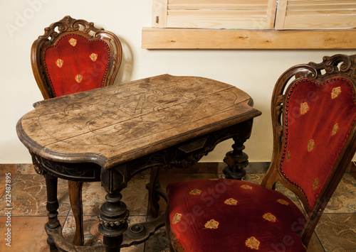 Old wooden handcrafted table with two antique chairs