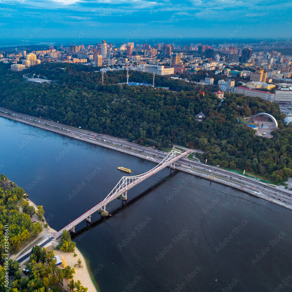Panoramic view of a modern city with a river. Skyline bird eye aerial view of the old part of the city under dramatic cloud sunset sky. General view of the right bank of Kiev with the Dnieper River, a