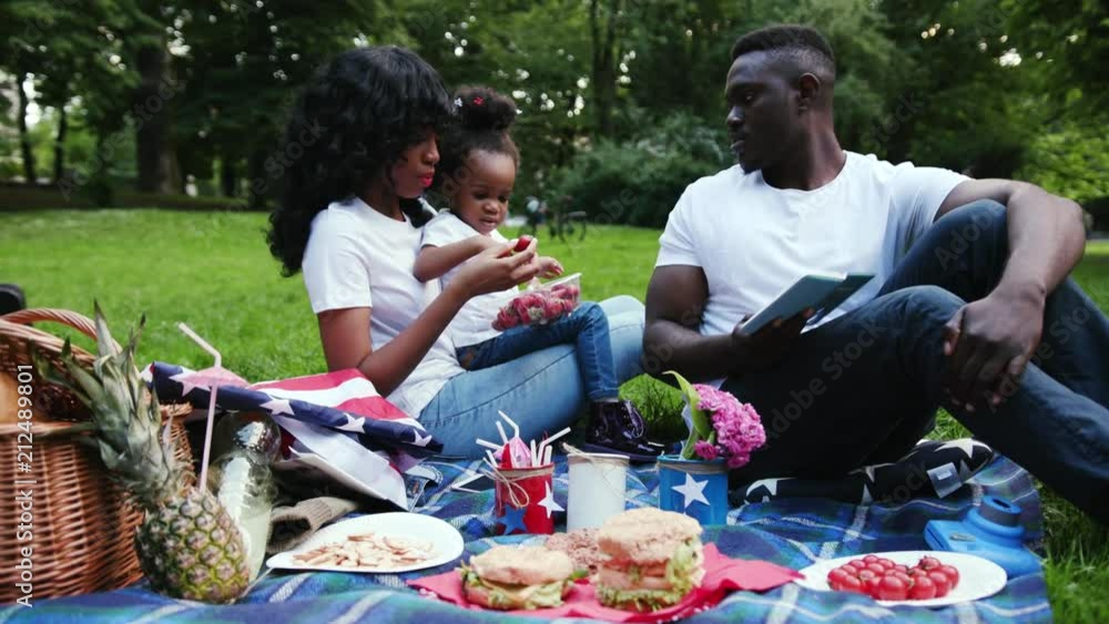 Slow motion african american couple with daughter in city park young man woman and child doing picnic eat strawberries having fun outdoor slow motion smiling relationship summer kid nature relax Slow motion african american couple with daughter in city park young man woman and child doing picnic eat strawberries having fun outdoor slow motion smiling relationship summer kid nature relax