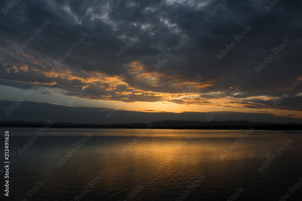 Beautiful sunset on the lake with the reflection of clouds