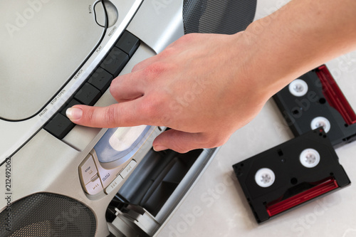 Female hand pushing open button on a music center.