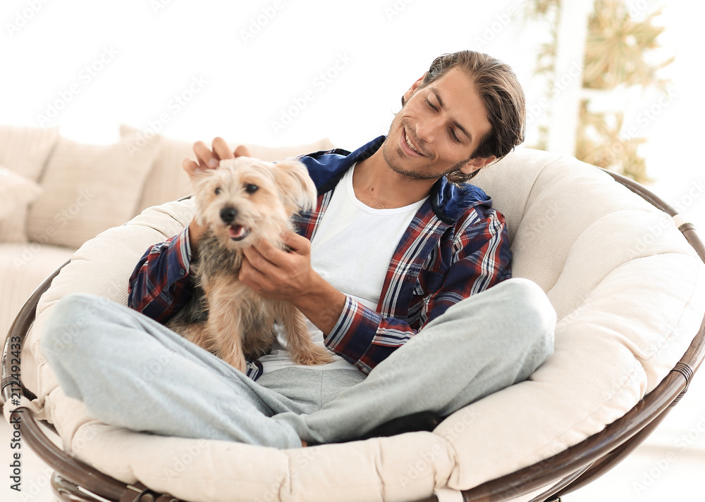 handsome guy with a dog sitting in a large armchair. handsome guy with a dog sitting in a large armchair.