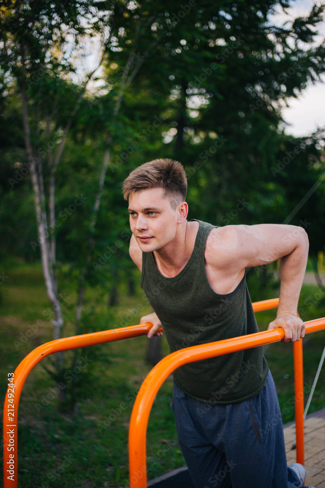 A young handsome guy is engaged in sports on horizontal bars. Healthy lifestyle