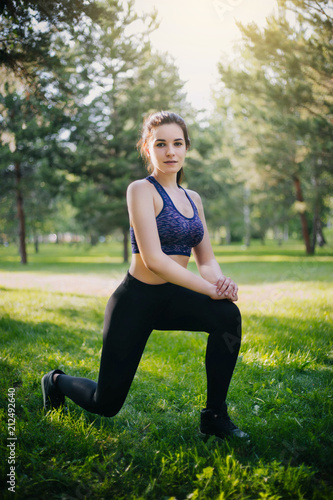 A beautiful girl in the park is engaged in sports. A model with clean skin and oboyatelnoy ulvbkoy in sportswear. Open-air trainings.