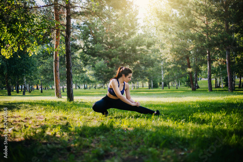 A beautiful girl in the park is engaged in sports. A model with clean skin and oboyatelnoy ulvbkoy in sportswear. Open-air trainings.