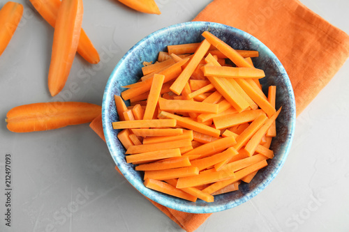 Bowl with cut ripe carrot on table, top view