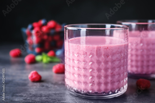 Delicious smoothie in glasses and fresh raspberries on table