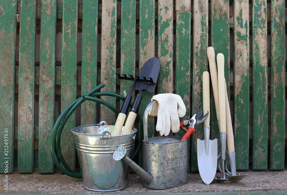 Set of gardening tools near wooden fence Set of gardening tools near wooden fence