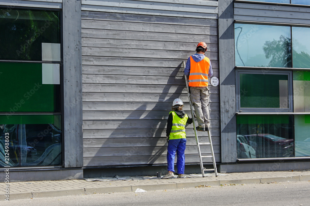 Fototapeta premium two workers paint the wall