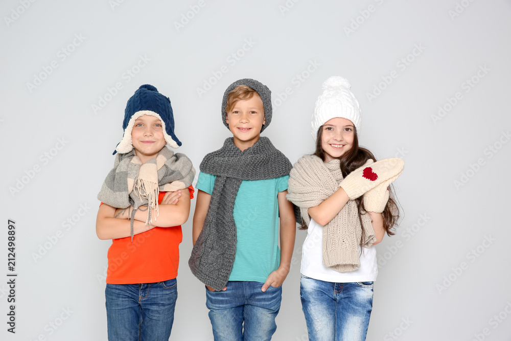 Cute little children in warm clothes posing on light background. Christmas celebration