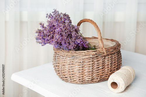 Wicker basket with lavender flowers on table indoors