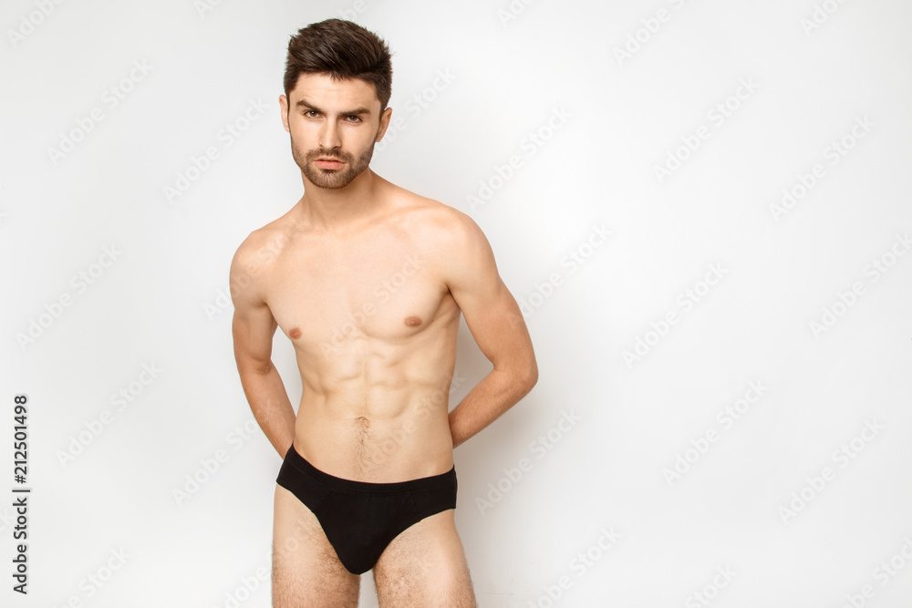 Strong stripped male model in black underwear on white background