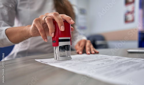 girl in the office puts a stamp on the documents photo