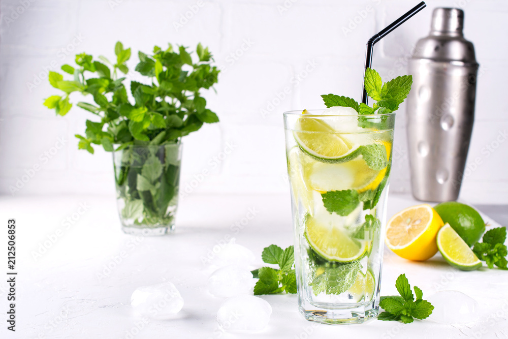 Summer mint lime refreshing cocktail mojito with ice in glass , fresh ingredients and cocktail shaker Summer mint lime refreshing cocktail mojito with ice in glass , fresh ingredients and cocktail shaker