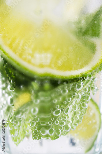 Mojito drink with lime, closeup . Macro concept of lemon , lime, mint  mojito with bubbles.  Summer  cold beverage.