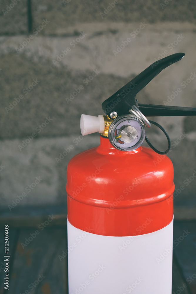 Naklejka premium Compact red fire extinguisher for auto or home on grey background. For fire emergencies.