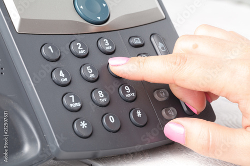 Close up of Finger dialing to make a phone call in office