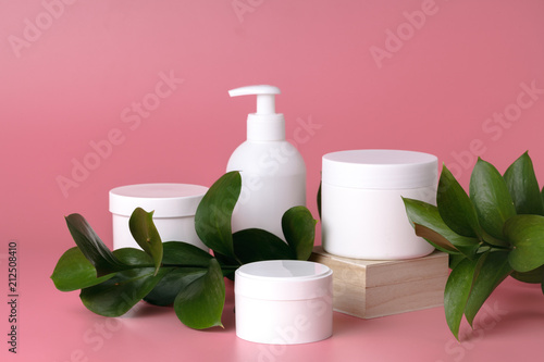 Cosmetic cream container and pink flowers on pink plaint  background