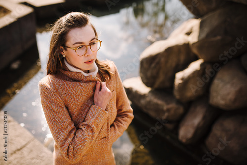 beautiful girl in a coat with glasses outdoors. portrait of a young woman outdoors