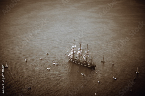 A large sailboat, bark goes into the sea surrounded by many yachts.
The last windjammer bark Kruzenstern. photo